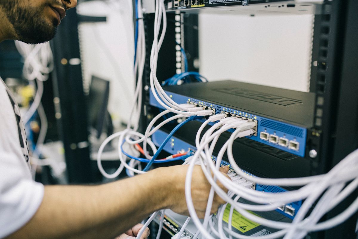 Field engineer terminating cables on rack-mounted network switches